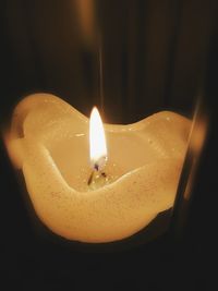 Close-up of lit candle against black background