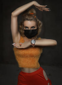 Portrait of beautiful young woman wearing mask against black background