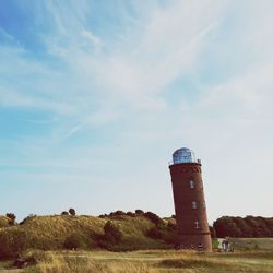 Lighthouse on field against sky