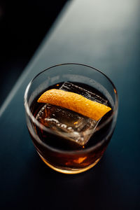 Whiskey cocktail in double old fashioned glass with orange peel garnish and one large ice cube