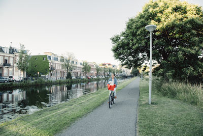 Man cycling on road in city against clear sky