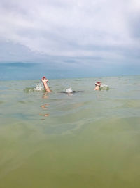 People swimming in sea against sky