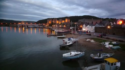 Boats moored at harbor in city at night