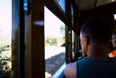Rear view of man looking through window