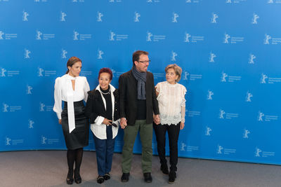 Full length of a young woman standing against blue wall