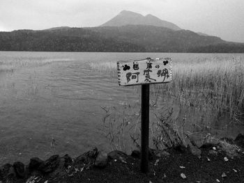 Information sign on wooden post in lake