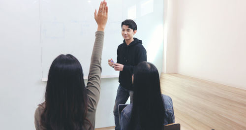 Females looking at man writing on whiteboard in classroom