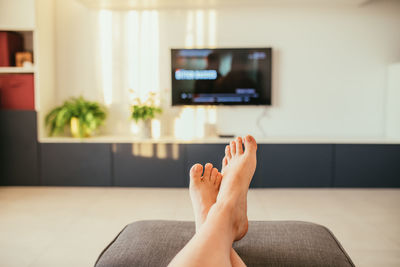 Low section of woman relaxing on sofa at home