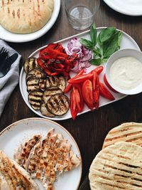 Flatlay dinner. grilled vegetables, grilled chicken and fresh herbs with pita and sauce