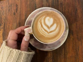 Cropped hand holding coffee on table