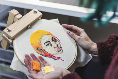 Hands of female craftsperson choosing threads for embroidery in studio