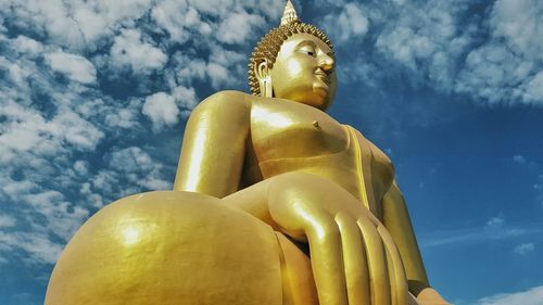 Low angle view of buddha statue against sky