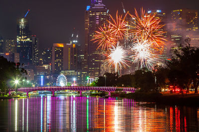 Firework display over illuminated buildings in city at night