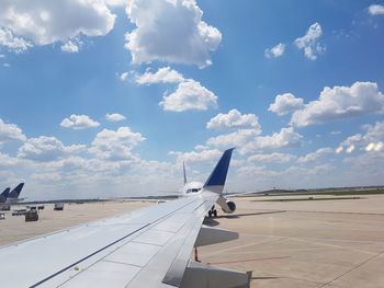 Airplane flying over airport runway against sky