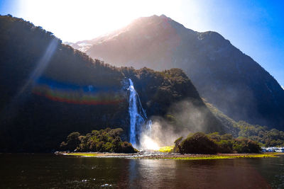 Scenic view of waterfall against rainbow in lake