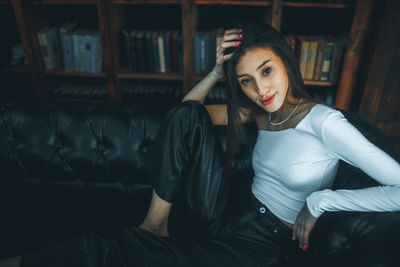 Portrait of young woman sitting on sofa at home