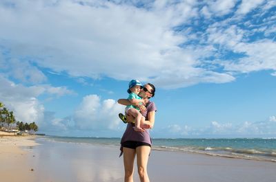 Woman standing at beach against sky