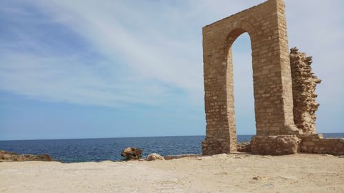 Stone structure by sea against sky