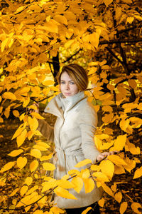 Portrait of woman standing amidst trees during winter