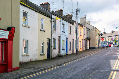 Road by buildings against sky in city