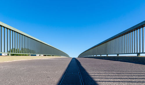 Surface level of empty bridge against clear blue sky