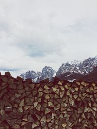 Stack of firewood against cloudy sky