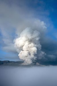 Smoke emitting from volcanic landscape against sky