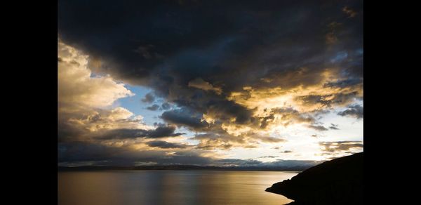 Scenic view of sea against dramatic sky during sunset