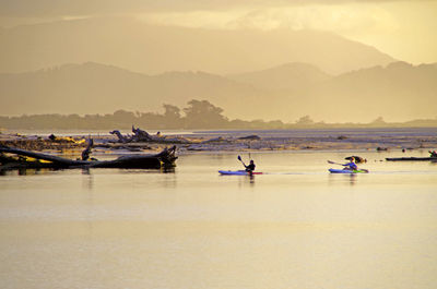 Boats in sea against sky during sunset