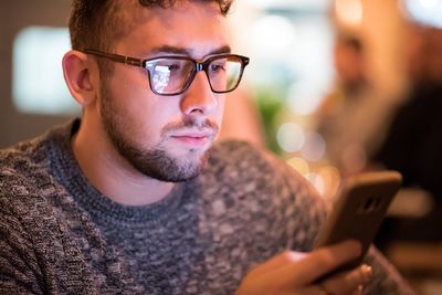 Close-up of young man using smart phone at home