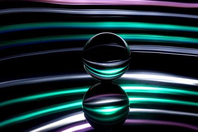 Crystal ball on glass table against colored background