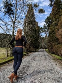 Rear view of woman walking on road amidst trees