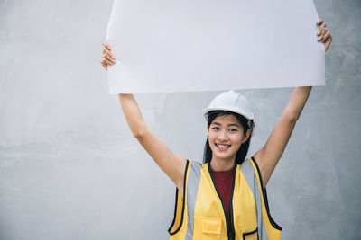 Portrait of a smiling young woman against wall