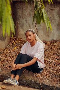 Portrait of beautiful young woman sitting on land