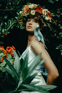 Portrait of beautiful woman standing by flowering plants