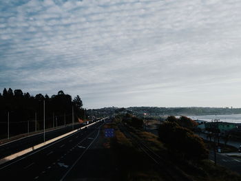 Railroad tracks by road against sky in city