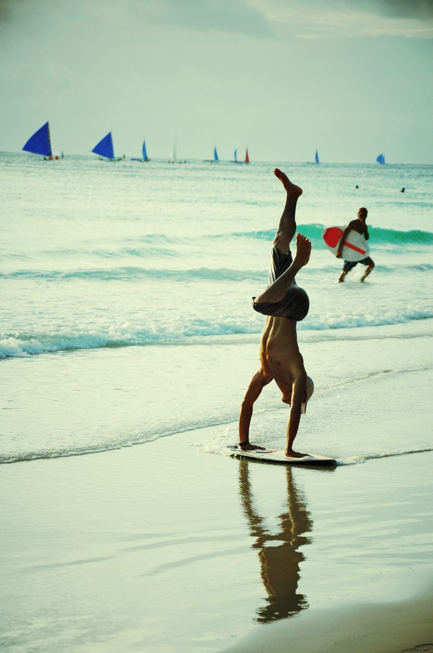 water, lifestyles, leisure activity, sea, full length, beach, men, jumping, mid-air, enjoyment, vacations, motion, sky, fun, sport, shore, skill, person