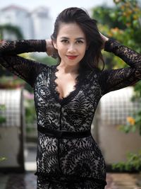 Portrait of young woman standing against fence