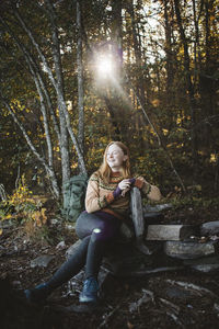 Smiling female hiker sitting in forest