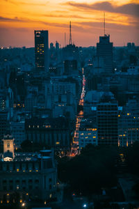 Illuminated buildings in city against sky at sunset