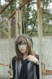 Portrait of woman standing amidst fence