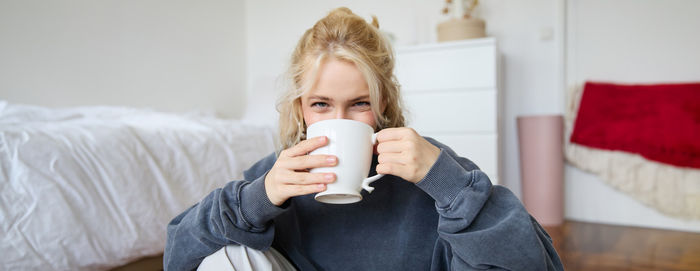 Portrait of young woman drinking coffee at home