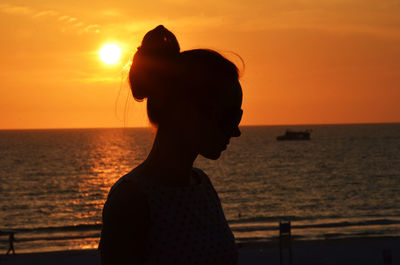 Silhouette woman standing against sea during sunset