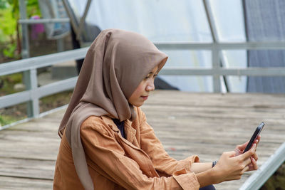 Beautiful young asian  muslim woman playing social media shoot from side angle