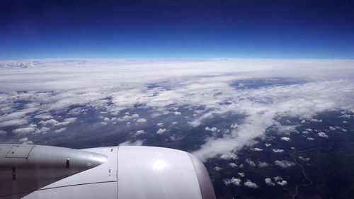 Aerial view of airplane wing over clouds