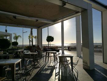 Empty chairs and tables at restaurant against clear sky