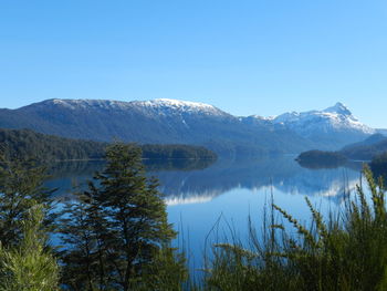 Scenic view of lake and mountains against clear blue sky