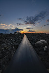 Surface level of empty road against sky during sunset