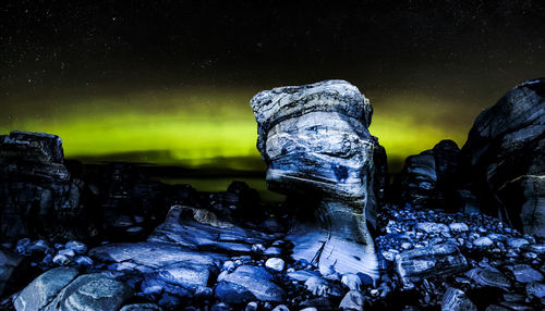 Rock formation on snow against sky at night