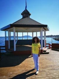 Portrait of woman standing at lakeshore against gazebo